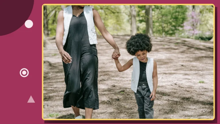 A parent and child walking hand in hand along a path outdoors.